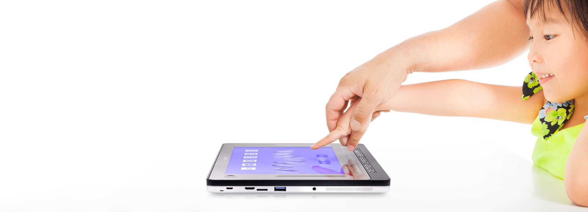 The photo shows a young girl placing her finger on the tablet with the help of her mother's hand.